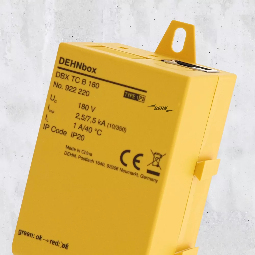 Close-up of a yellow DEHNbox surge protection device showing product label and mounting tab.
