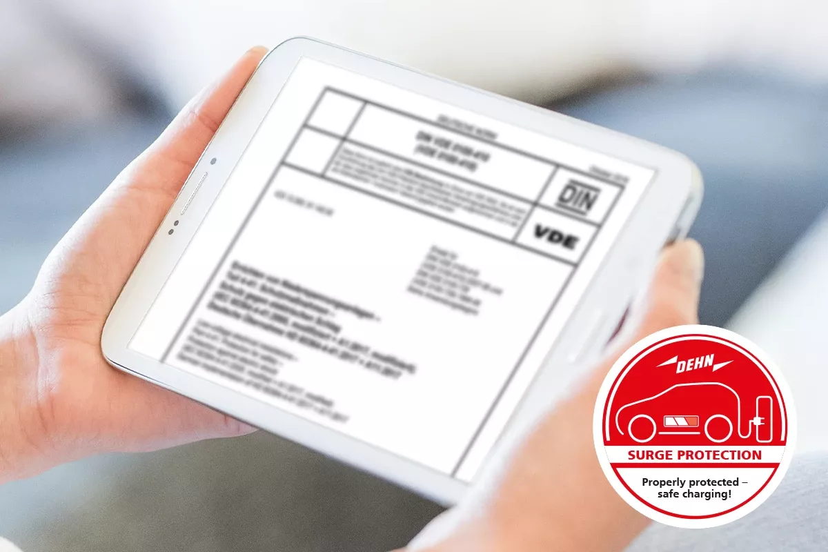 Tablet displaying DIN/VDE standards document, with DEHN surge protection badge for safe electric vehicle charging.